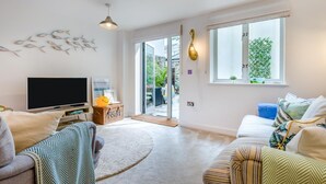 Een moderne woonkamer met een flatscreen televisie, twee banken, een salontafel en een groot raam met uitzicht op het landschap.