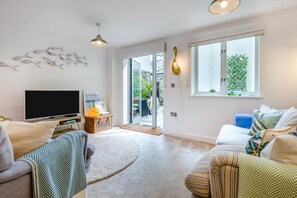A modern living room with a flat-screen TV, two sofas, a coffee table, and a large window with a view of the outdoors. - 1 Bed in Fowey (oc-saila) (Fowey)