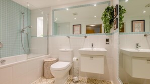 Een badkamer met een bad, toilet, wastafel en spiegel.