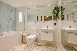 A bathroom with a bathtub, toilet, sink, and a mirror. - 1 Bed in Fowey (oc-saila) (Fowey)