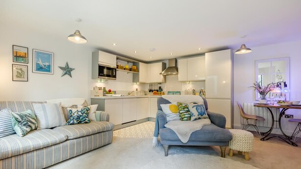 Een moderne woonkamer met een bank, een blauwe fauteuil en een eethoek met een tafel en stoelen.