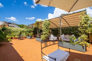 A covered outdoor seating area with a metal bench, a table, and chairs. - Sunny Rooftop Apartment  (Firenze)