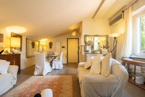A spacious living room with a sofa, chairs, a dining table, and a large mirror. - Sunny Rooftop Apartment  (Firenze)
