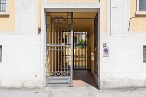 A gated entrance to a building with a narrow passageway leading to a door. - Sunny Rooftop Apartment  (Firenze)