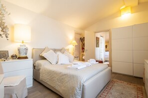 A neatly arranged bedroom with a large bed, bedside lamps, a nightstand, and a wardrobe. - Sunny Rooftop Apartment  (Firenze)