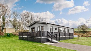 Une maison mobile de plain-pied, dotée d’une terrasse à l’avant et d’un escalier menant à l’entrée.