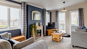 Un salon chaleureux avec une cheminée, un téléviseur et des fauteuils confortables.