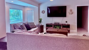 Ein Wohnzimmer mit einer Couch, einem Couchtisch, einem Fernseher und einem Deckenventilator.