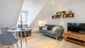 A modern living room with a dining area, a sofa, a TV, and a bookshelf. - 1 Bed in St. Ives (oc-h27240) (St Ives)