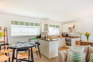 Una cocina moderna con armarios blancos, una isla central y un comedor con una mesa redonda y sillas.