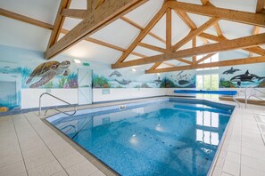 Ein Innenpool mit Wandgemälden aus Meereslebewesen, Holzbalken an der Decke und einem gefliesten Boden.