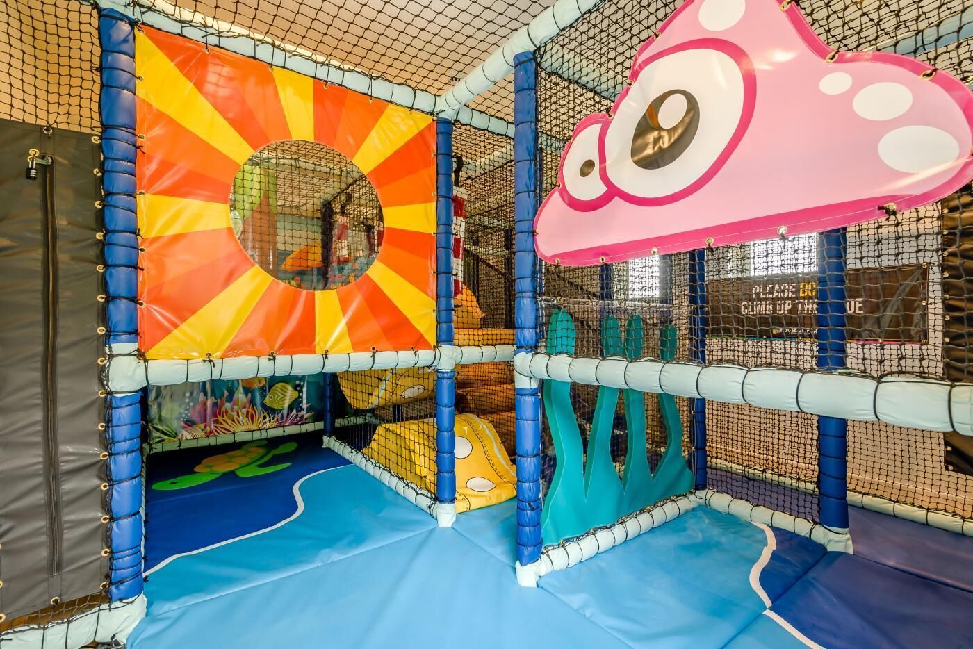 An indoor play area with a colorful play structure, including a slide and climbing elements.