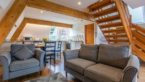 Ein Loft mit Holztreppe, Essbereich und Küche.