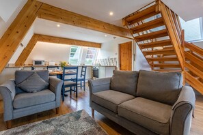 Ein Loft mit Holztreppe, Essbereich und Küche.
