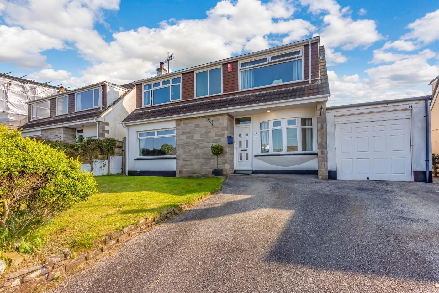 A two-story house with a garage, a driveway, and a well-maintained lawn.
