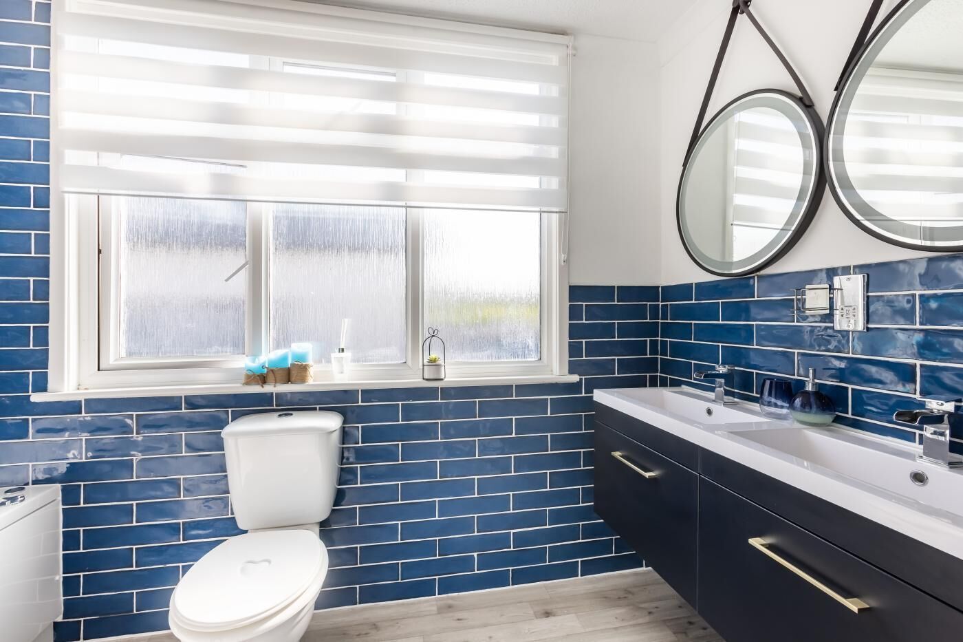 A bathroom with a toilet, a sink, and a window with blinds.