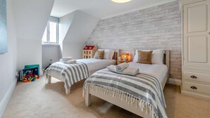 Ein Schlafzimmer mit zwei Betten, einer Holzwand, einem Fenster und einer kleinen Spielecke mit Spielzeug.