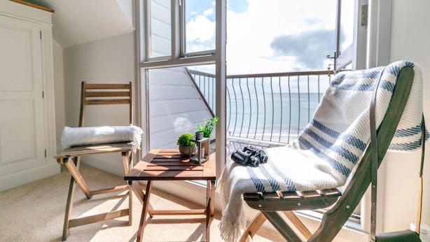 Ein Balkon mit Stuhl, Tisch und Blick auf das Meer.
