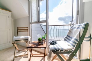 A balcony with a chair, a small table, and a view of the ocean. - 2 Bed in Looe (oc-t27479) (Looe)