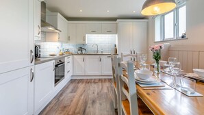 Eine moderne Küche mit weißen Schränken, einer Holzausziehtafel und einem Essbereich mit einem Tisch für zwei Personen.