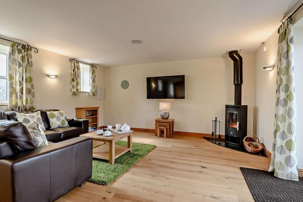 A modern living room with a fireplace, leather sofa, and a flat-screen TV.