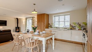 Una cucina moderna con mobili impiallacciati in legno, un tavolo da pranzo con sedie e un piano cottura integrato.