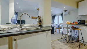 Eine moderne Küche mit Spüle, ein Essbereich mit Tisch und Stühlen sowie Blick zum Wohnzimmer.