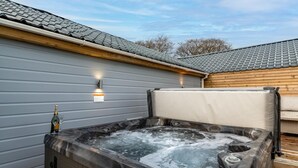 Ein Whirlpool mit einer Holzterrasse und einem Gebäude im Hintergrund.