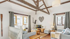 Un accogliente soggiorno con una scala in legno, una televisione e una decorazione a forma di cuore sulla parete.