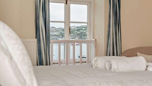 Une chambre à coucher avec un lit, une vue sur un port de plaisance et une fenêtre avec des rideaux.