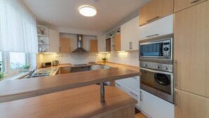 Een moderne keuken met houten kastjes, een roestvrijstalen oven, een magnetron en een spoelbak.