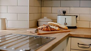A kitchen with a wooden countertop, a toaster, a cutting board with bread, and a white mug. - 2 Bed in Thornbury (oc-r27561) (Thornbury)