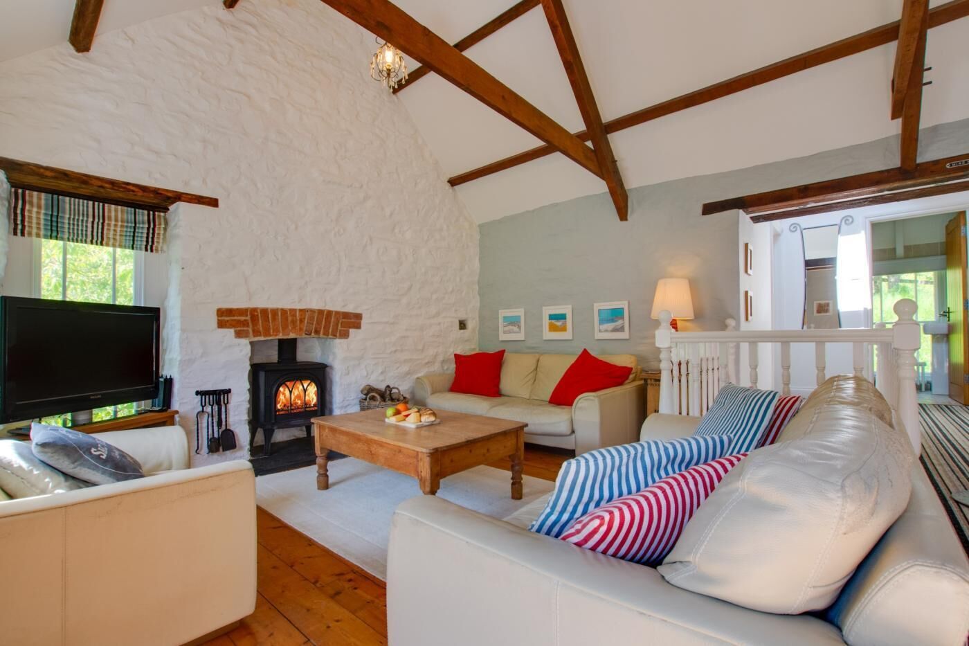 A cozy living room with a fireplace, a sofa, a television, and a wooden coffee table.