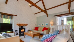 A cozy living room with a fireplace, a sofa, a television, and a wooden coffee table. - 3 Bed in Aberporth (oc-g27666) (Aberporth)