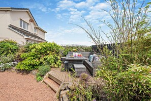 Eine Terrasse mit Gartenmöbeln, einer Steinmauer und verschiedenen Pflanzen.