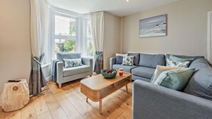 A modern living room with two sofas, a coffee table, and a window with curtains. - 4 Bed in Westward Ho (oc-h27657) (Westward Ho!)