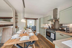 A modern kitchen with a dining area, wooden flooring, and light-colored cabinetry. - 4 Bed in Westward Ho (oc-h27657) (Westward Ho!)