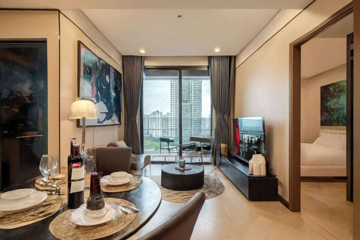 A modern hotel room with a dining area, a TV, and a large window with a city view.