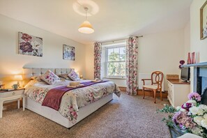 Une chambre à coucher avec un lit, un bureau, une chaise et une fenêtre avec des rideaux.