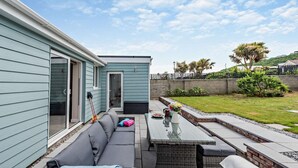 Eine Terrasse mit Sofa, Tisch und einem kleinen Gartenbereich.
