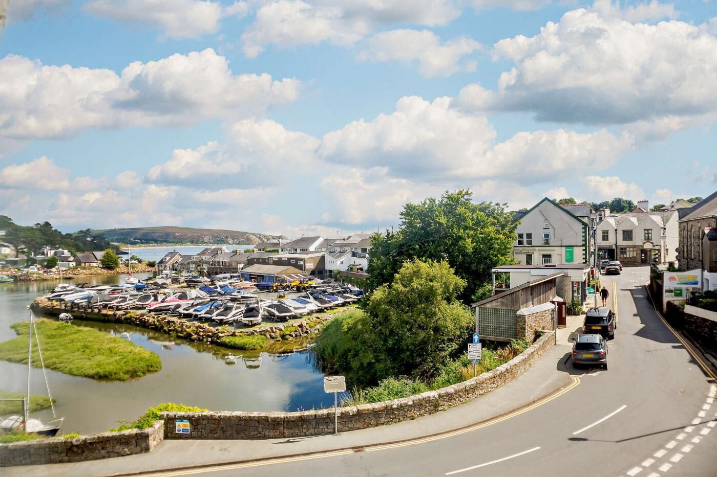 A coastal town with a marina, stone buildings, and a road curving through the scene.