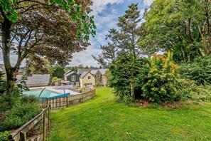 A residential area with a swimming pool, wooden fence, and houses with stone walls.