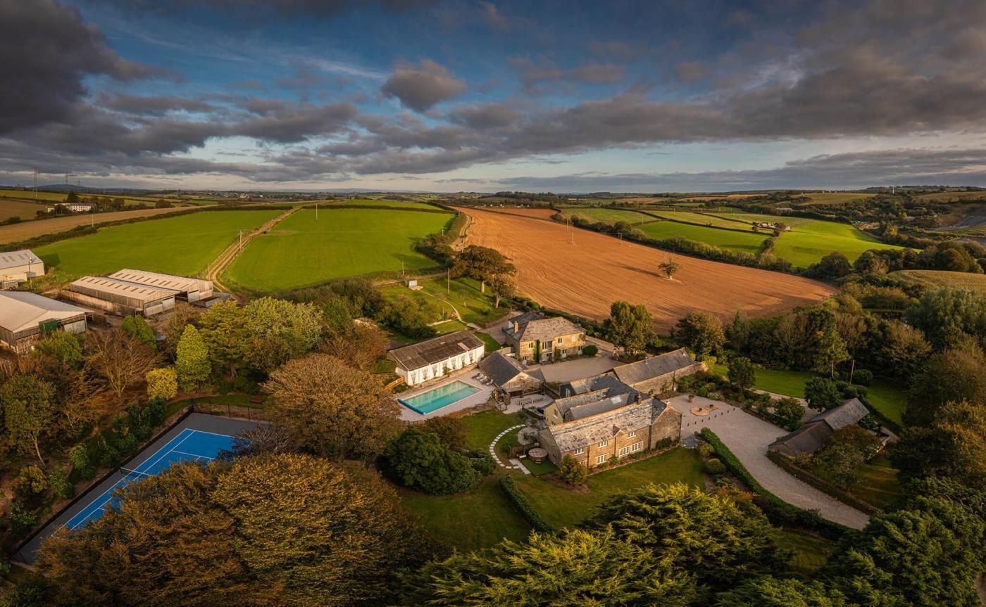 A large estate with multiple buildings, a swimming pool, and expansive green fields.