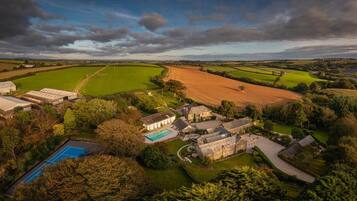 A large estate with multiple buildings, a swimming pool, and expansive green fields.
