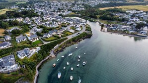 Vue aérienne d’une ville côtière avec des maisons résidentielles, une marina où sont amarrés plusieurs bateaux et une route sinueuse qui mène à la ville.