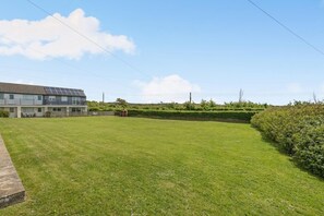 A residential building with a flat roof, solar panels, and a well-maintained lawn. - 2 Bed in Bude (oc-b27662) (Bude)