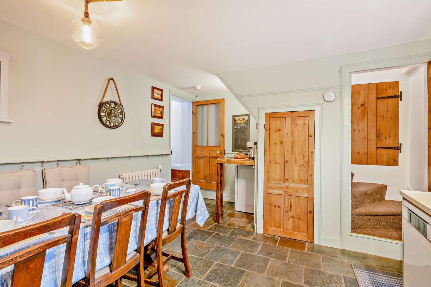 A dining area with a round table, chairs, and a clock on the wall.