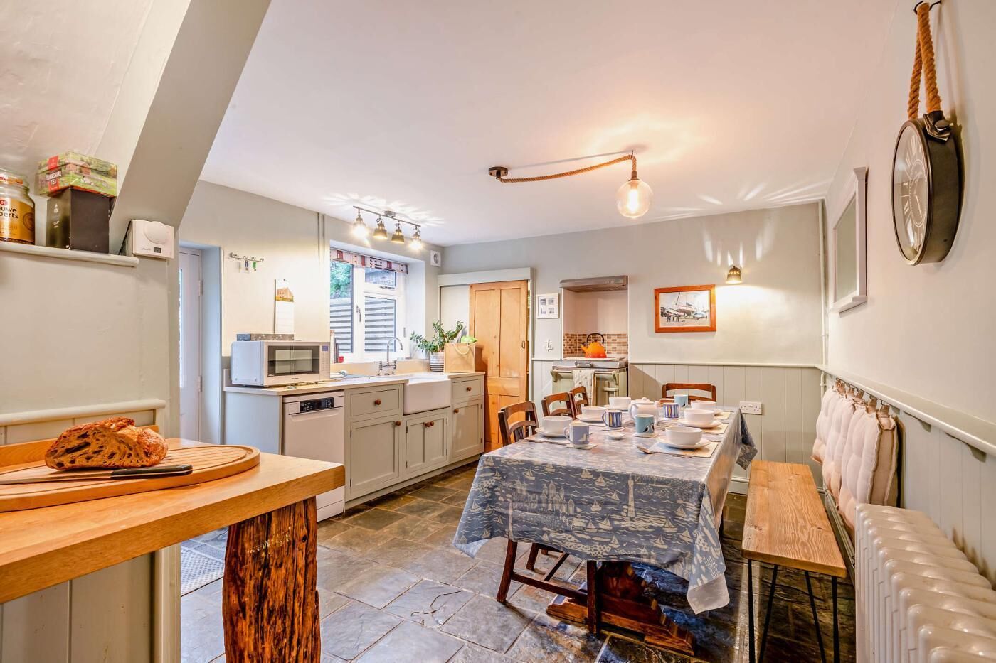 A cozy kitchen with a dining area, featuring a wooden table, a built-in oven, and a hanging light fixture.