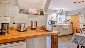A modern kitchen with a built-in espresso machine, toaster, kettle, and a wooden cutting board with bread. - 3 Bed in Wells-next-the-Sea (oc-c27939) (Wells-next-the-Sea)