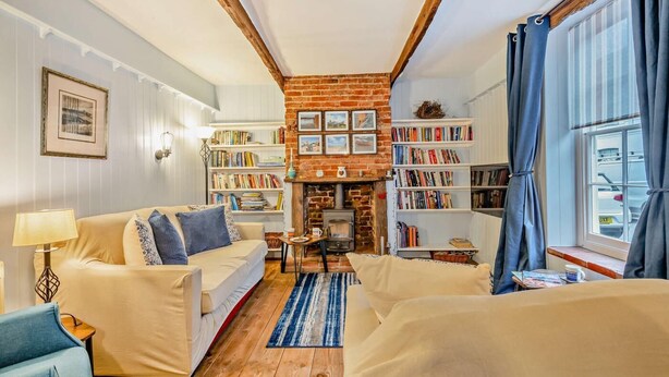 A cozy living room with a fireplace, bookshelves, and a comfortable sofa. - 3 Bed in Wells-next-the-Sea (oc-c27939) (Wells-next-the-Sea)